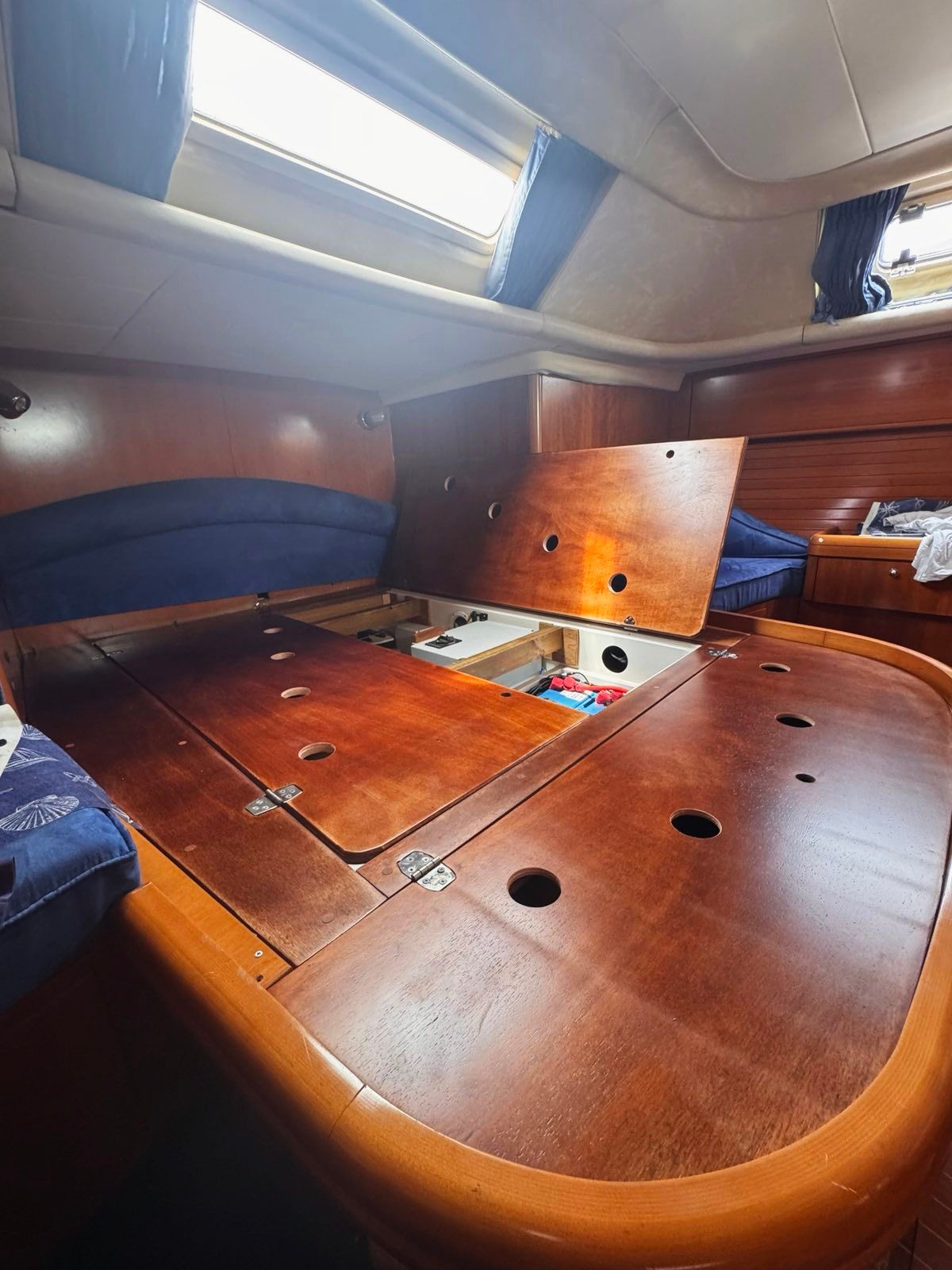 Wooden bed base in a boat cabin, with lift-up panels for access underneath
